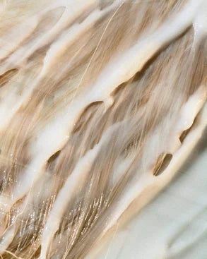 Close-up of Soft Again Moisturising Conditioner on blonde hair on a light background